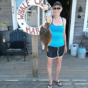 Alice Garrity holding flounder catch on dock at Whale Creek Marina